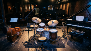 Instrumenty jazzowe na pustej scenie przed koncertem Współgłosów. Festiwal Łódź Wielu Kultur – nastrojowy widok na kontrabas i perkusję w blasku reflektorów.